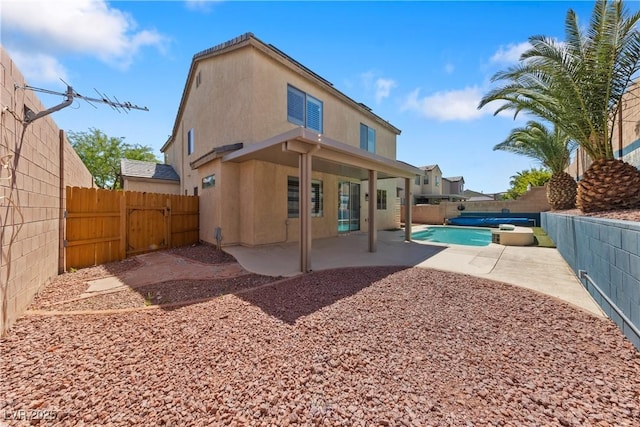 back of house featuring a fenced backyard, a patio, stucco siding, and a gate