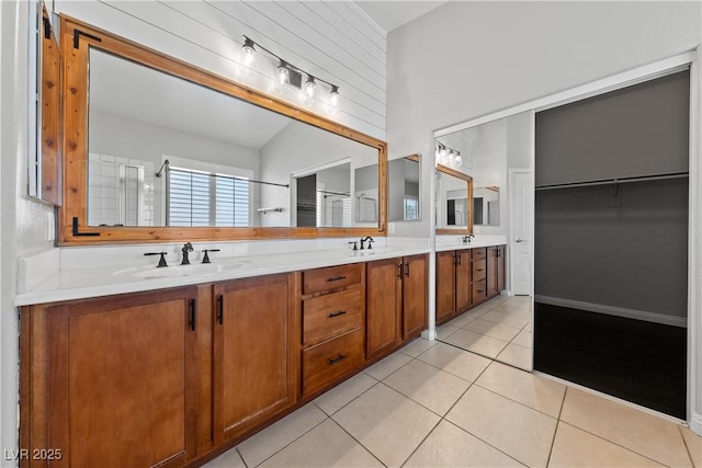 full bath featuring double vanity, tile patterned flooring, and a spacious closet