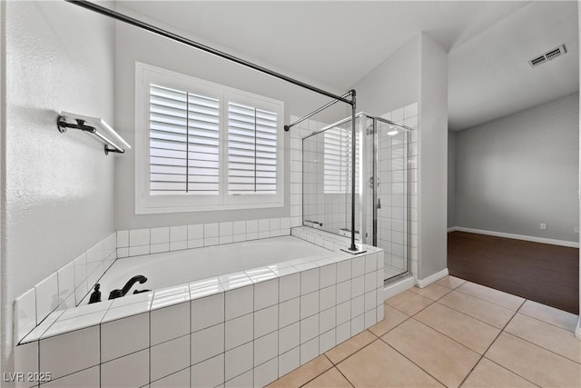 bathroom featuring tile patterned floors, a stall shower, a garden tub, and baseboards