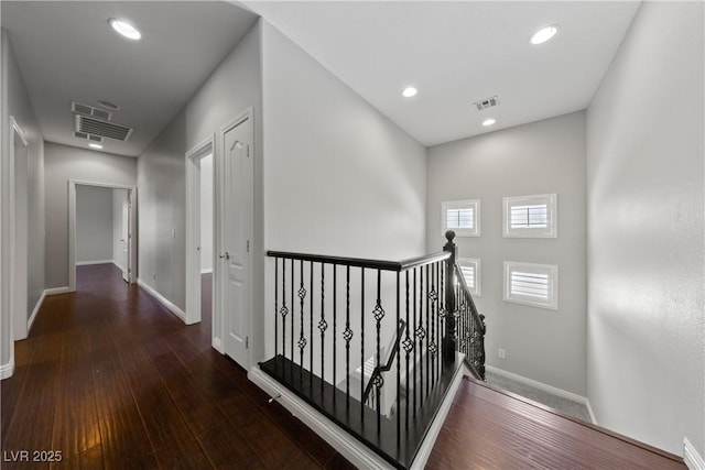 hallway with an upstairs landing, baseboards, wood-type flooring, and recessed lighting