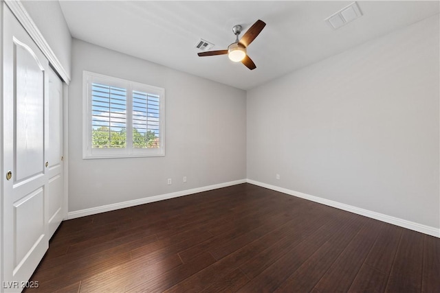 unfurnished bedroom featuring baseboards, dark wood-style floors, a closet, and ceiling fan