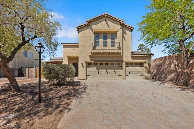 view of front facade featuring a balcony, decorative driveway, stucco siding, and an attached garage