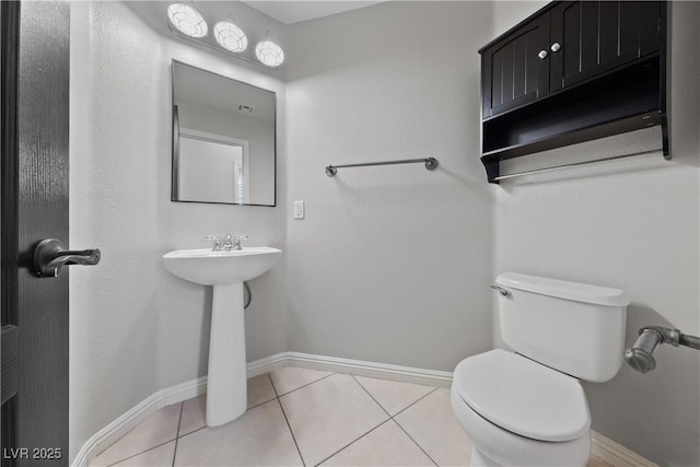 bathroom featuring baseboards, toilet, and tile patterned flooring