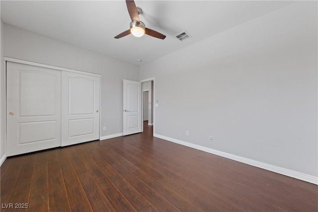 unfurnished bedroom featuring baseboards, a closet, dark wood-style flooring, and ceiling fan