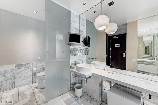 4381 W Flamingo Rd Unit 3206, Las Vegas, NV 89103 - full bathroom featuring tile walls, marble finish floors, toilet, and a sink