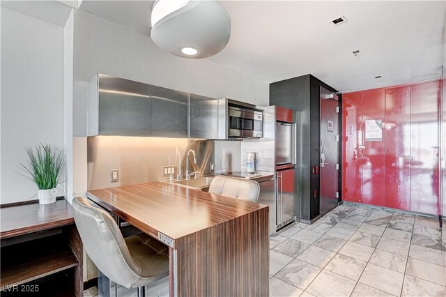 4381 W Flamingo Rd Unit 3206, Las Vegas, NV 89103 - kitchen with stainless steel microwave, a sink, light marble finish flooring, cooktop, and light countertops