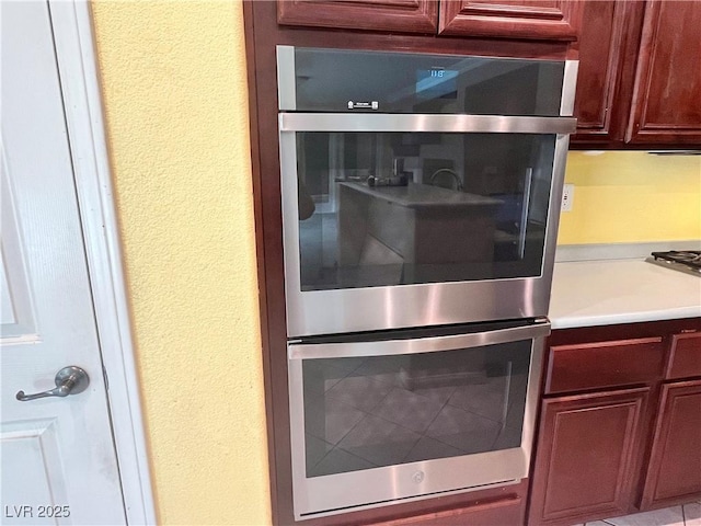 2112 Merganser Ct, North Las Vegas, NV 89084 - kitchen view of double oven, a textured wall, light countertops, and reddish brown cabinets