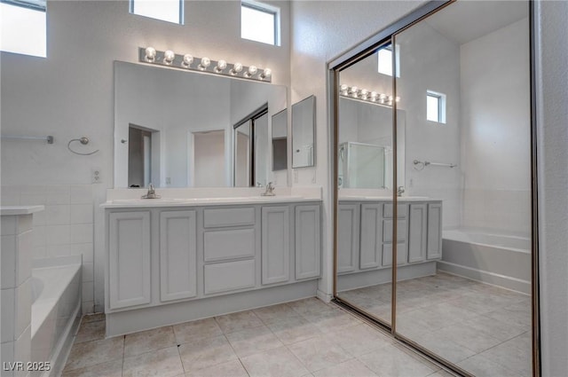 full bathroom featuring a garden tub, healthy amount of natural light, double vanity, tile patterned floors, and a towering ceiling