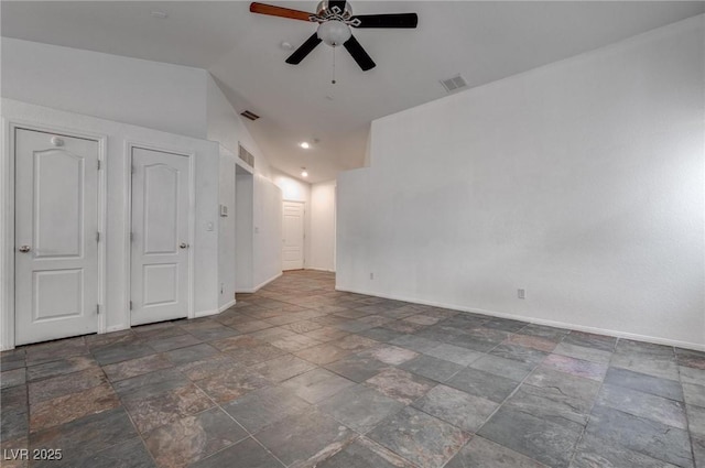spare room featuring ceiling fan, stone tile floors, baseboards, and lofted ceiling