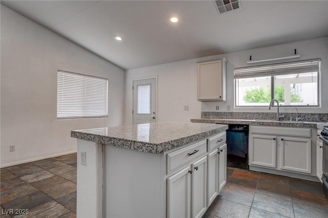 kitchen featuring black dishwasher, a sink, stone tile floors, a center island, and lofted ceiling