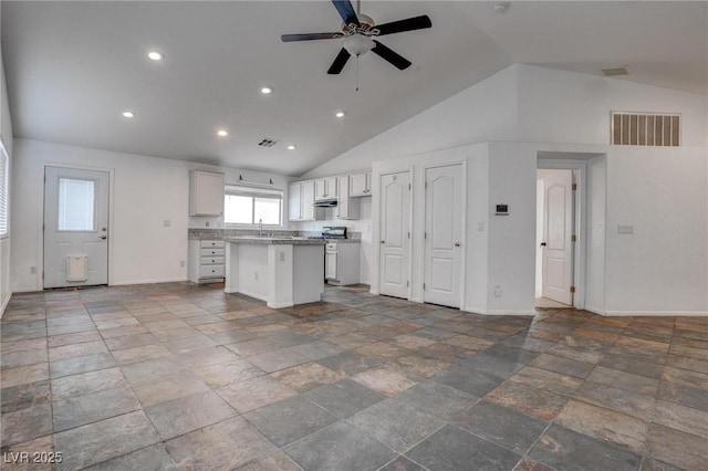 kitchen with a center island, baseboards, ceiling fan, white cabinets, and high vaulted ceiling