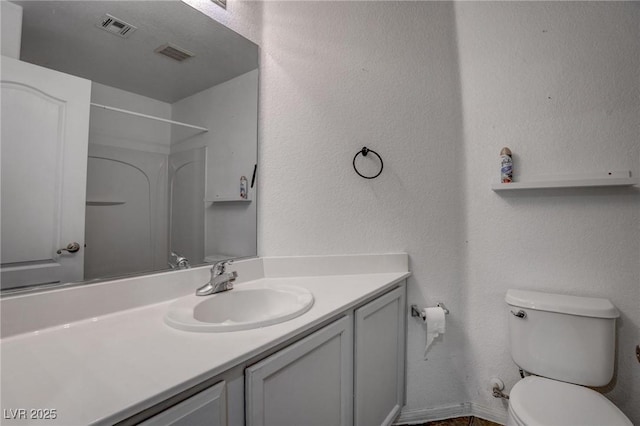 bathroom featuring toilet, vanity, and a shower