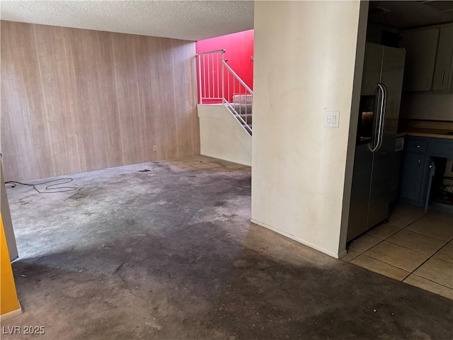 unfurnished room with wooden walls, stairs, and a textured ceiling