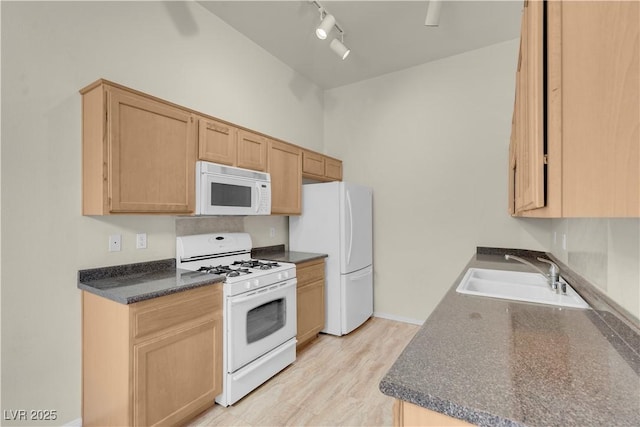 kitchen with white appliances, a sink, dark countertops, rail lighting, and light brown cabinetry