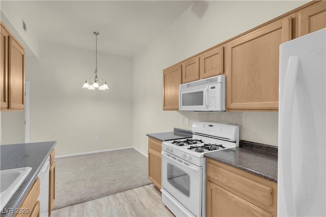 kitchen featuring white appliances, dark countertops, a chandelier, light colored carpet, and hanging light fixtures