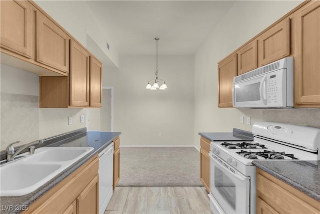 kitchen featuring white appliances, a sink, a chandelier, dark countertops, and light carpet