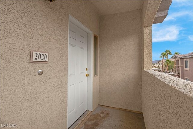 property entrance featuring a balcony and stucco siding