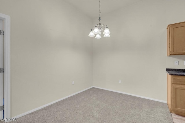 unfurnished dining area with a chandelier, light colored carpet, baseboards, and vaulted ceiling