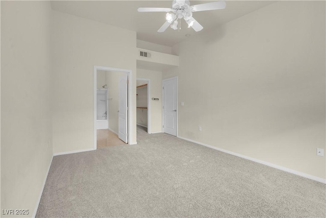 unfurnished bedroom with light carpet, a spacious closet, and baseboards