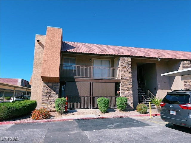 view of property featuring uncovered parking and stairs
