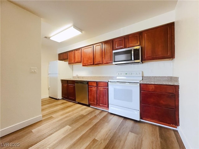 kitchen featuring stainless steel appliances, light wood-type flooring, baseboards, and a sink