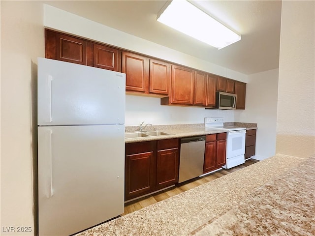 kitchen with stainless steel appliances, a sink, light wood finished floors, and light countertops