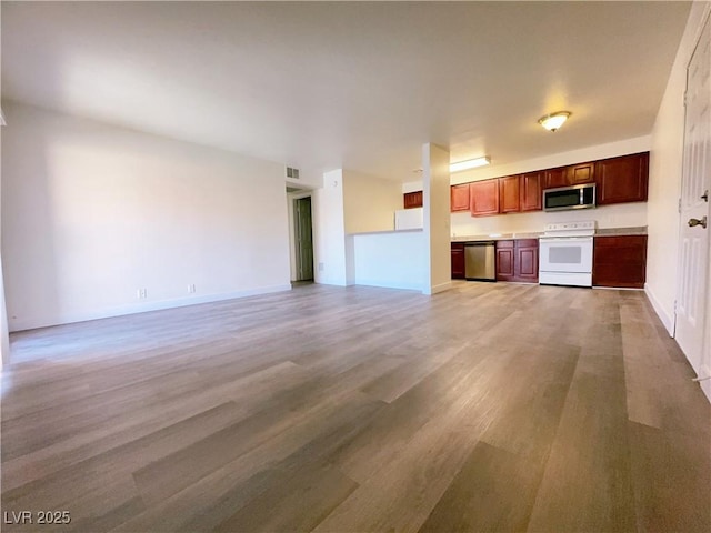 kitchen featuring stainless steel appliances, light countertops, light wood finished floors, and open floor plan