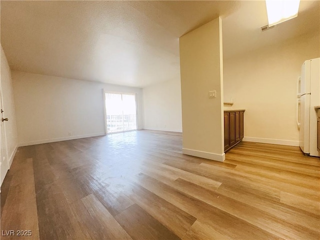 unfurnished room with light wood-type flooring and baseboards