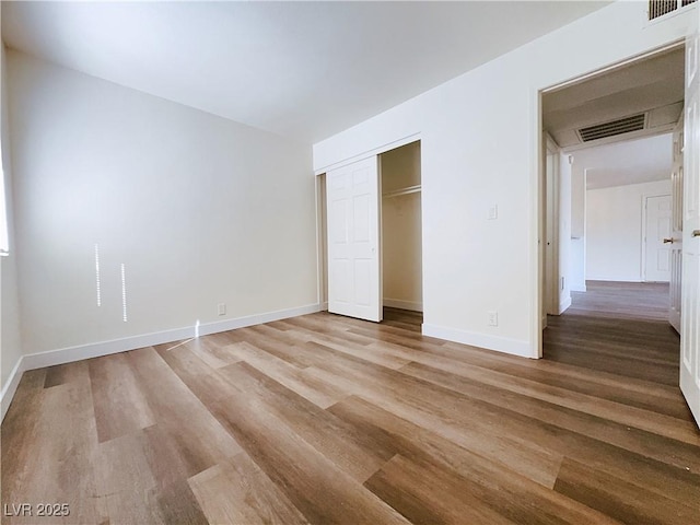 unfurnished bedroom with light wood finished floors, a closet, and baseboards