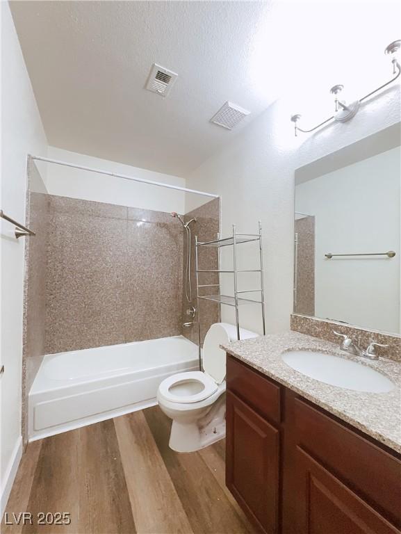bathroom featuring wood finished floors, shower / bathtub combination, toilet, and vanity