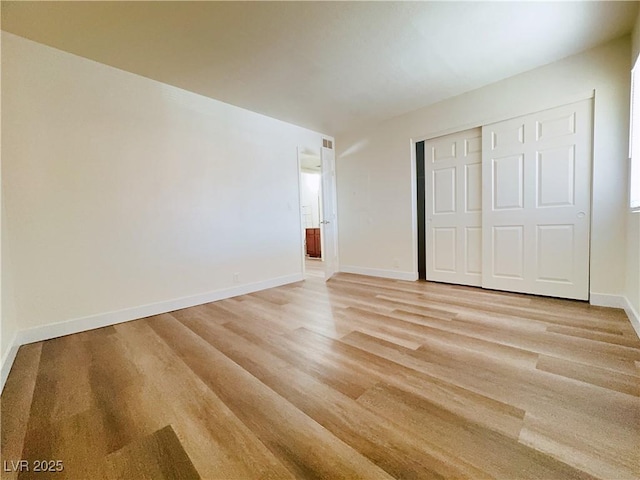 unfurnished bedroom with light wood-style floors, baseboards, and a closet