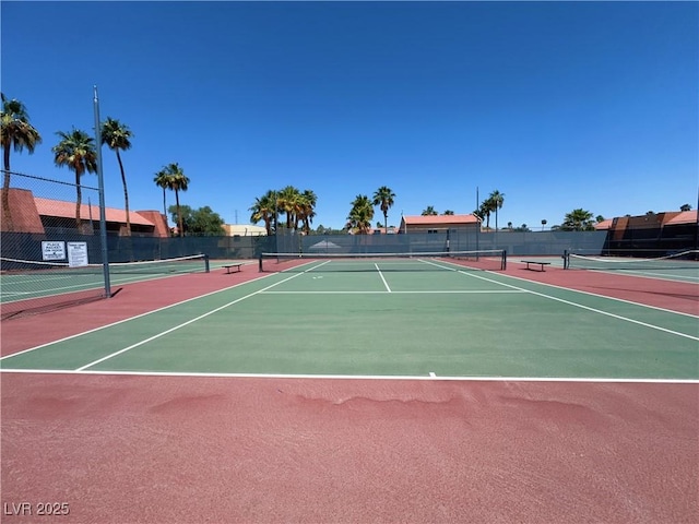 view of tennis court featuring community basketball court and fence