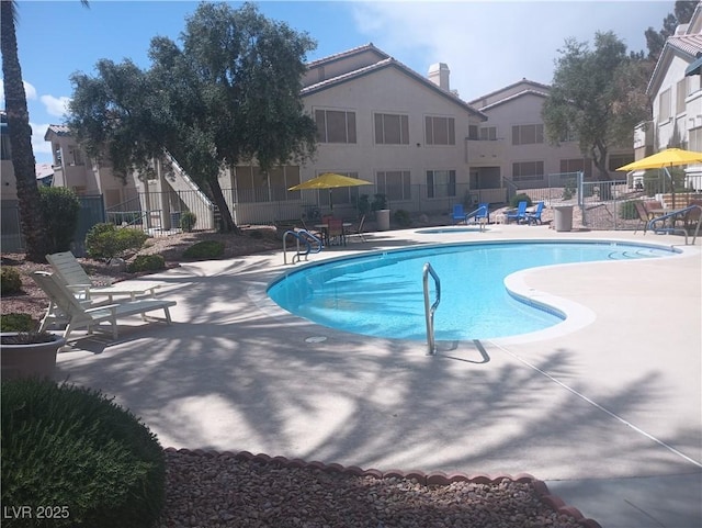 community pool with fence and a patio area
