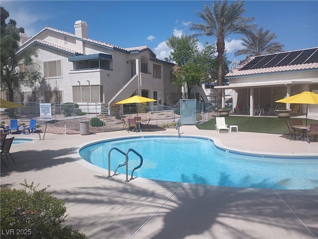 community pool with fence and a patio