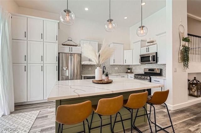 2470 Lower Meadows Ave, Henderson, NV 89052 - kitchen featuring stainless steel appliances, a center island, white cabinets, backsplash, and a breakfast bar area