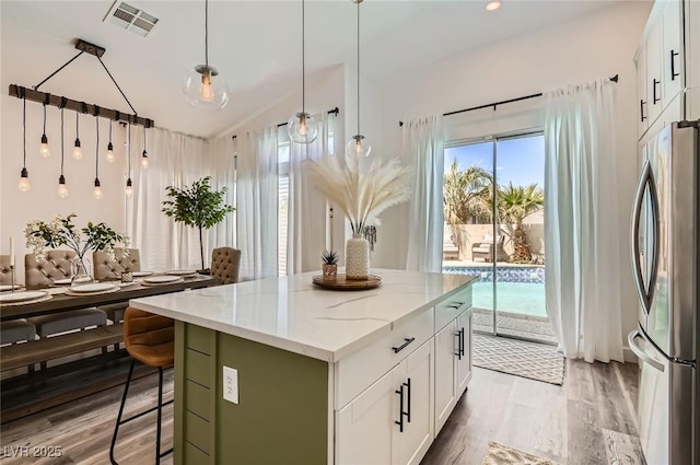 2470 Lower Meadows Ave, Henderson, NV 89052 - kitchen with freestanding refrigerator, a kitchen island, light wood finished floors, white cabinets, and light stone counters