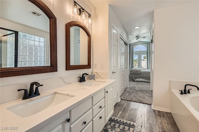 2470 Lower Meadows Ave, Henderson, NV 89052 - ensuite bathroom featuring wood finished floors, a garden tub, double vanity, recessed lighting, and baseboards