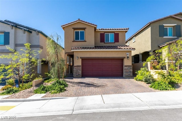 view of front of house featuring a tile roof, decorative driveway, an attached garage, stucco siding, and stone siding