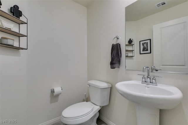 bathroom with baseboards, toilet, and a sink