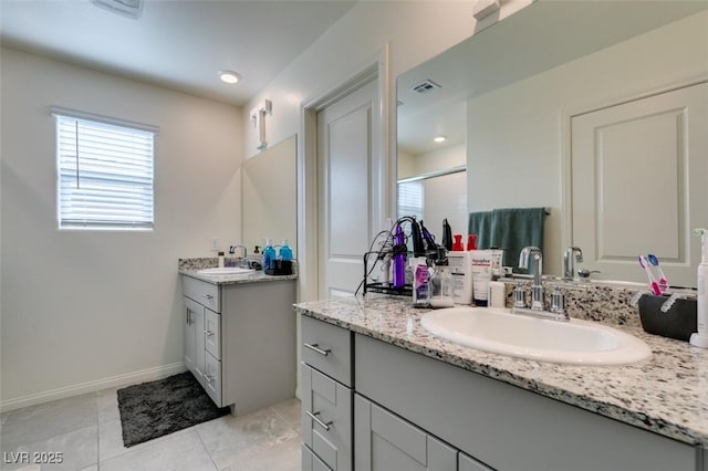 full bath with a shower stall, tile patterned floors, and two vanities
