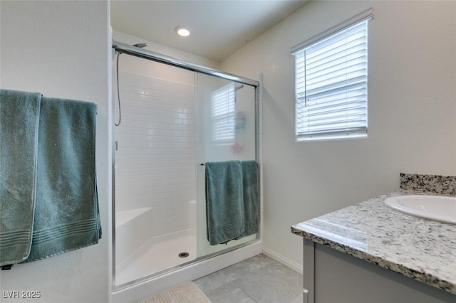 full bath featuring a stall shower, vanity, and baseboards