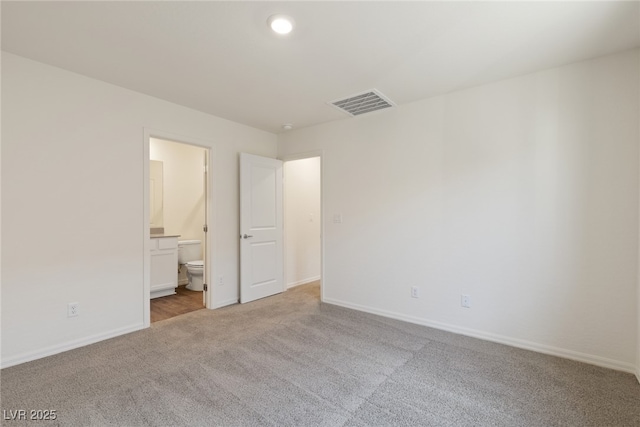 unfurnished bedroom featuring carpet floors, baseboards, and ensuite bathroom