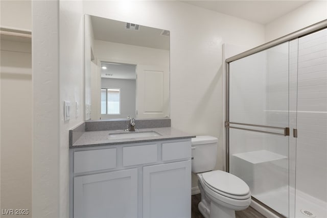 bathroom featuring a shower stall, toilet, and vanity