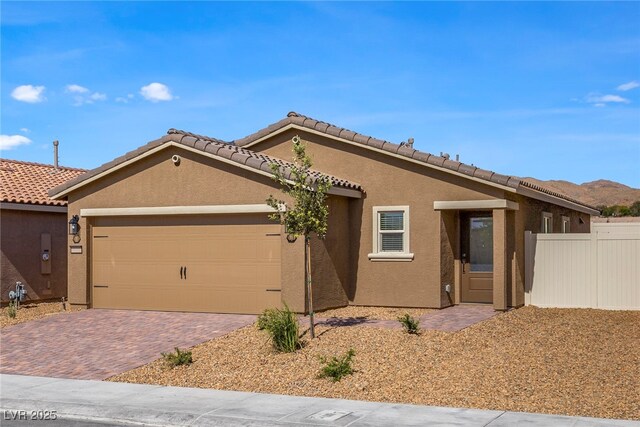 single story home with stucco siding, a garage, decorative driveway, fence, and a tile roof