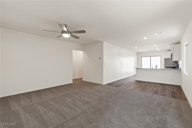 unfurnished living room with dark colored carpet, ceiling fan, baseboards, and recessed lighting