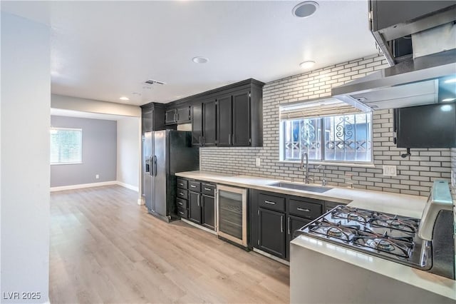 kitchen featuring wine cooler, a sink, dark cabinetry, tasteful backsplash, and recessed lighting