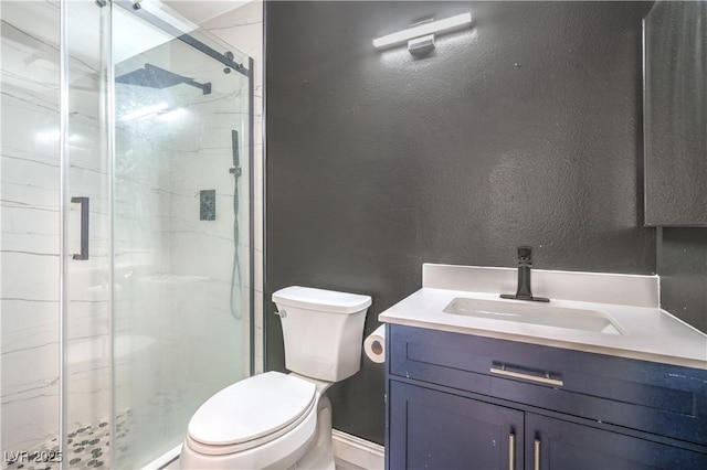 full bath with a marble finish shower, toilet, vanity, a textured wall, and baseboards