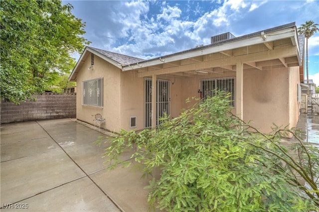 rear view of property with a patio, stucco siding, fence, and roof with shingles