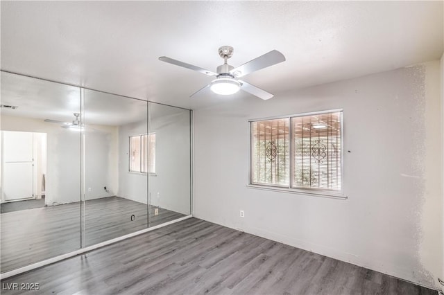 unfurnished bedroom featuring wood finished floors, multiple windows, and a closet