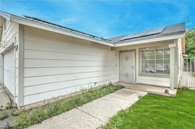 property entrance featuring roof mounted solar panels and a garage